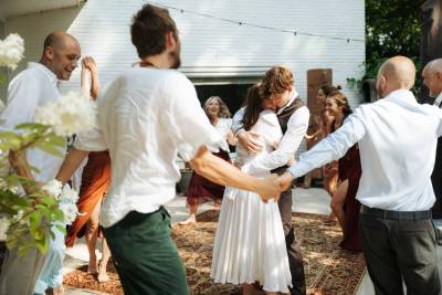Bruidspaar danst en omarmt elkaar omringd door vrolijke gasten tijdens hun bruiloft buiten